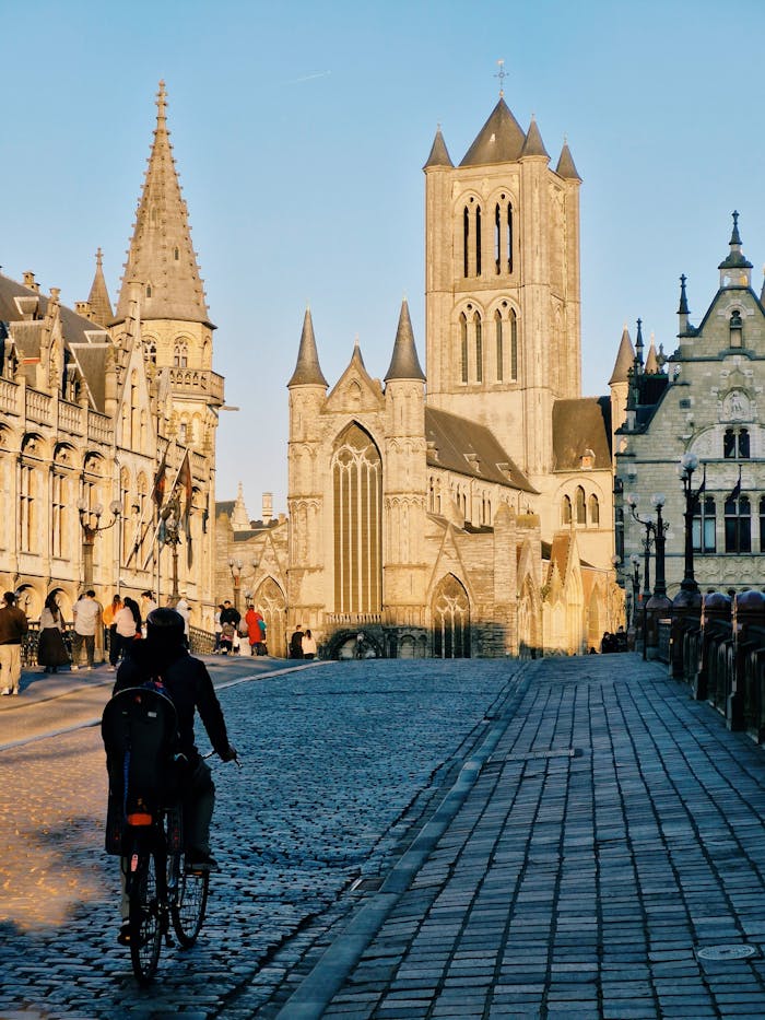 Explore the historic charm of Ghent's medieval architecture as a cyclist passes by at dusk.